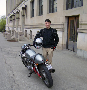 Teagan Prince and the 1975 Honda CB550k he built from seven boxes of parts over the last academic year. Student and motorbike standing in front of John Bapst.